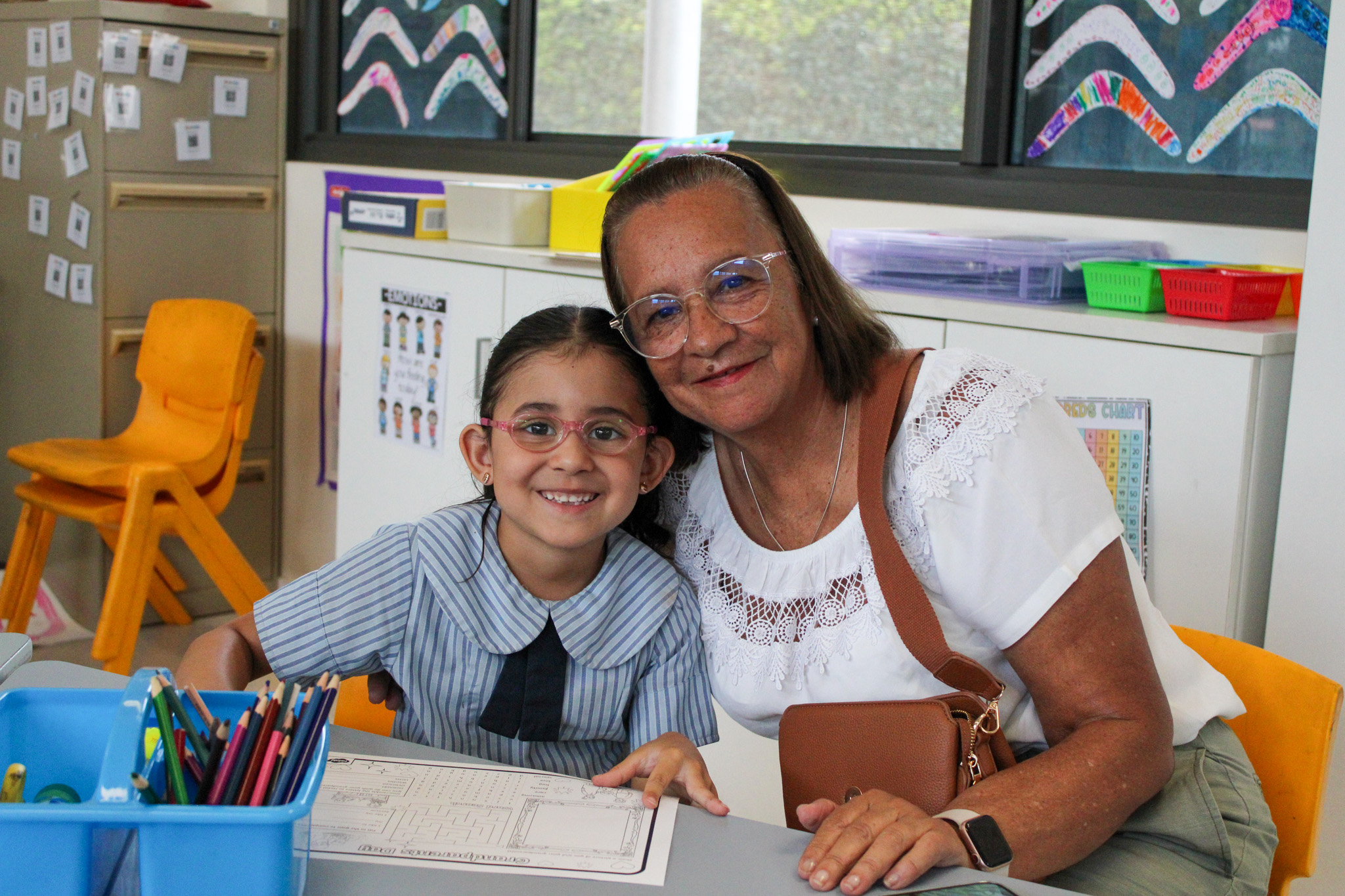 Student and adult sitting together in a classroom reviewing schoolwork, emphasising individual support and positive learning relationships