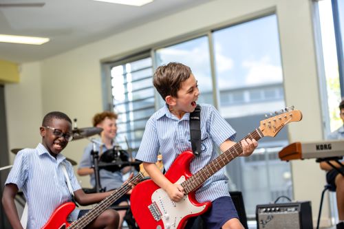 Students playing electric guitars during a music lesson, highlighting collaboration, creativity and engagement in school music programs