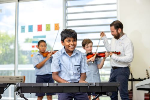Students learning and performing instruments in a classroom setting with teacher guidance, supporting skill development and musical learning