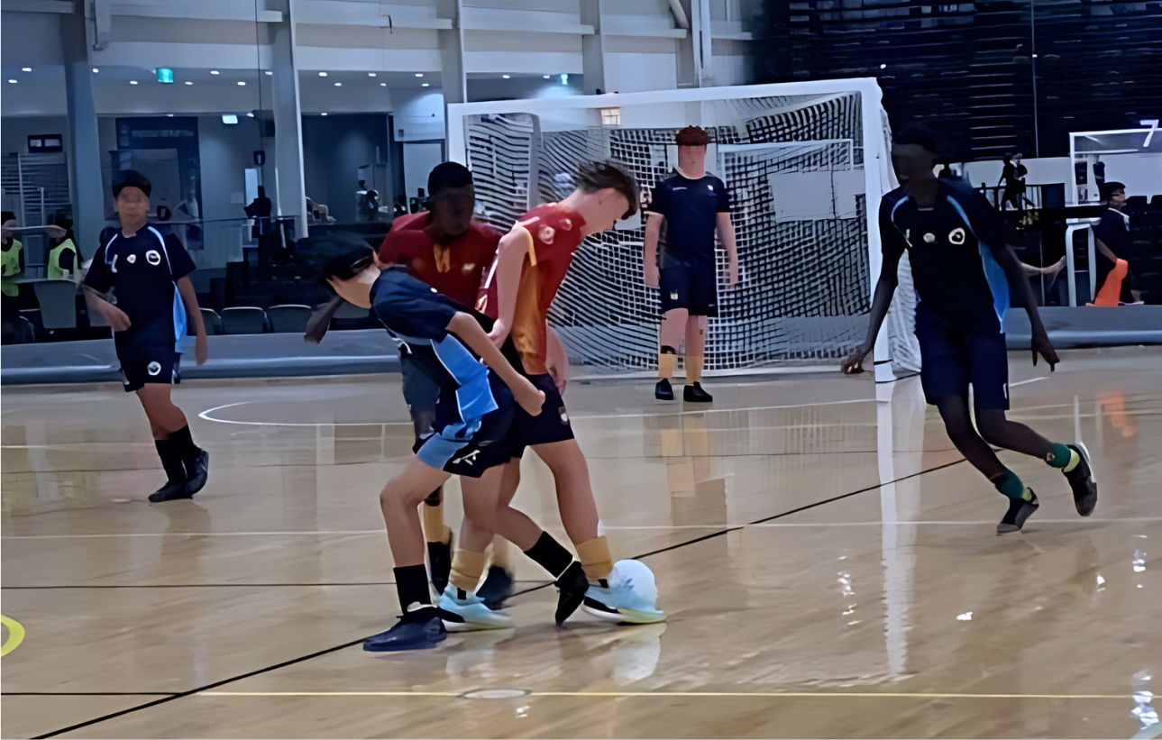 Students participating in indoor futsal match, demonstrating teamwork, skill and active engagement in school sport