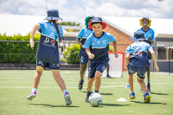 Junior students playing soccer outdoors, promoting physical activity, teamwork and enjoyment of sport