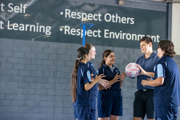 Students and coach discussing teamwork and sports skills with focus on respect and collaboration