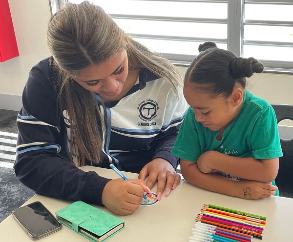 Older student supporting a younger student with a classroom activity promoting mentoring and engagement