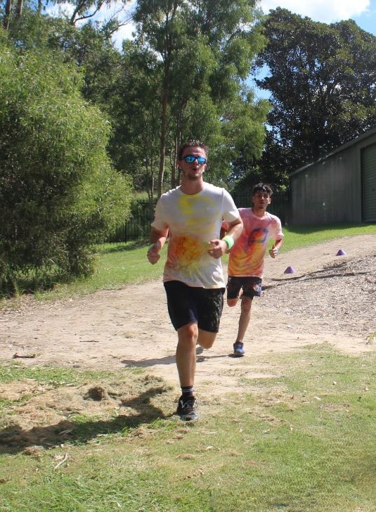 Students running along a track during a school activity, encouraging fitness, perseverance and outdoor participation
